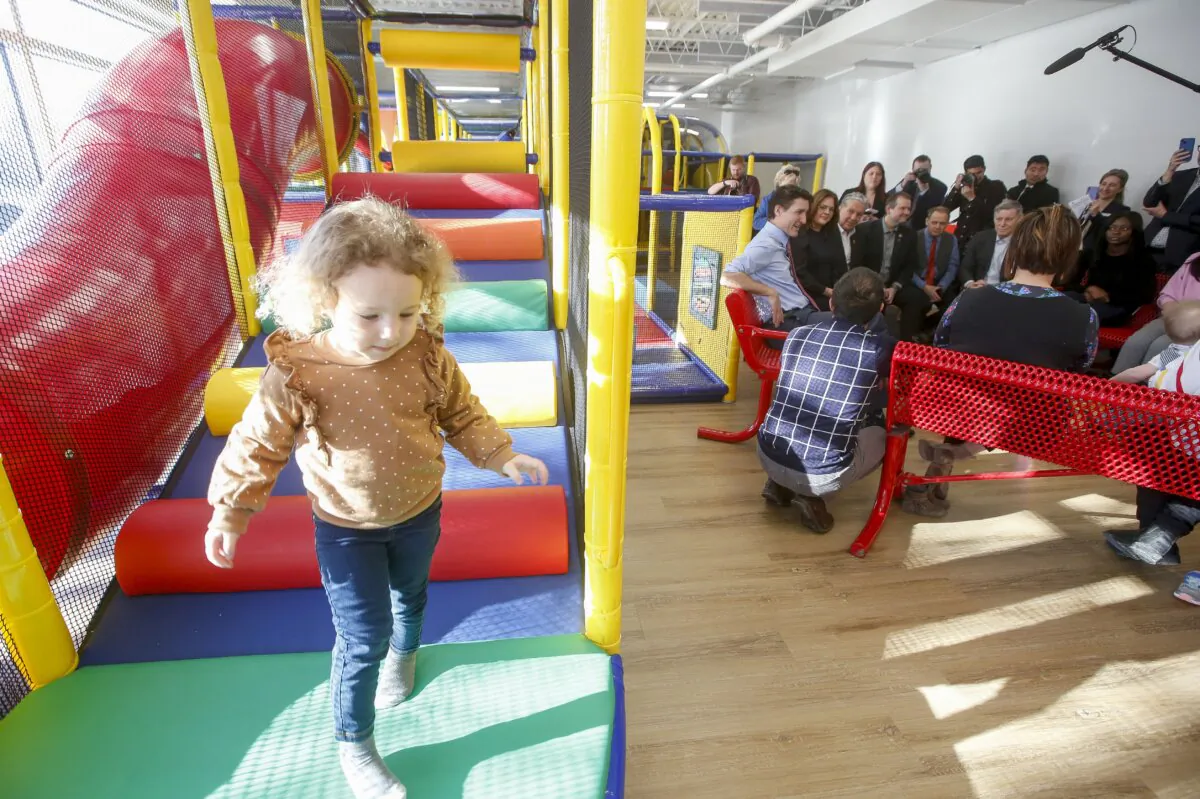 A child plays on a play structure as Prime Minister Justin Trudeau talks to parents at the YMWCA daycare in Winnipeg about the federal $10-a-day child care plan for Manitoba, on March 3, 2023. (The Canadian Press/John Woods)