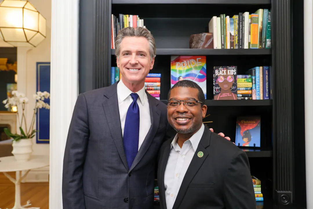 California Gov. Gavin Newsom (L) signs a state bill prohibiting local school boards from excluding textbooks and instructional materials containing "inclusive and diverse perspectives," accompanied by the bill's author Assemblyman Corey Jackson (D-Perris) in Sacramento, Calif., on Sept. 25, 2023. (Courtesy of Office of Governor Gavin Newsom)