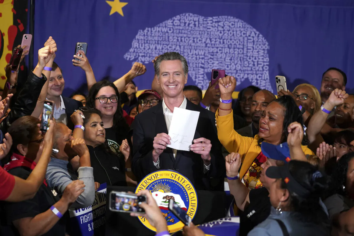 California Gov. Gavin Newsom signs the fast food bill surrounded by fast food workers at the SEIU Local 721 in Los Angeles on Sept. 28, 2023. (Damian Dovarganes/AP Photo)