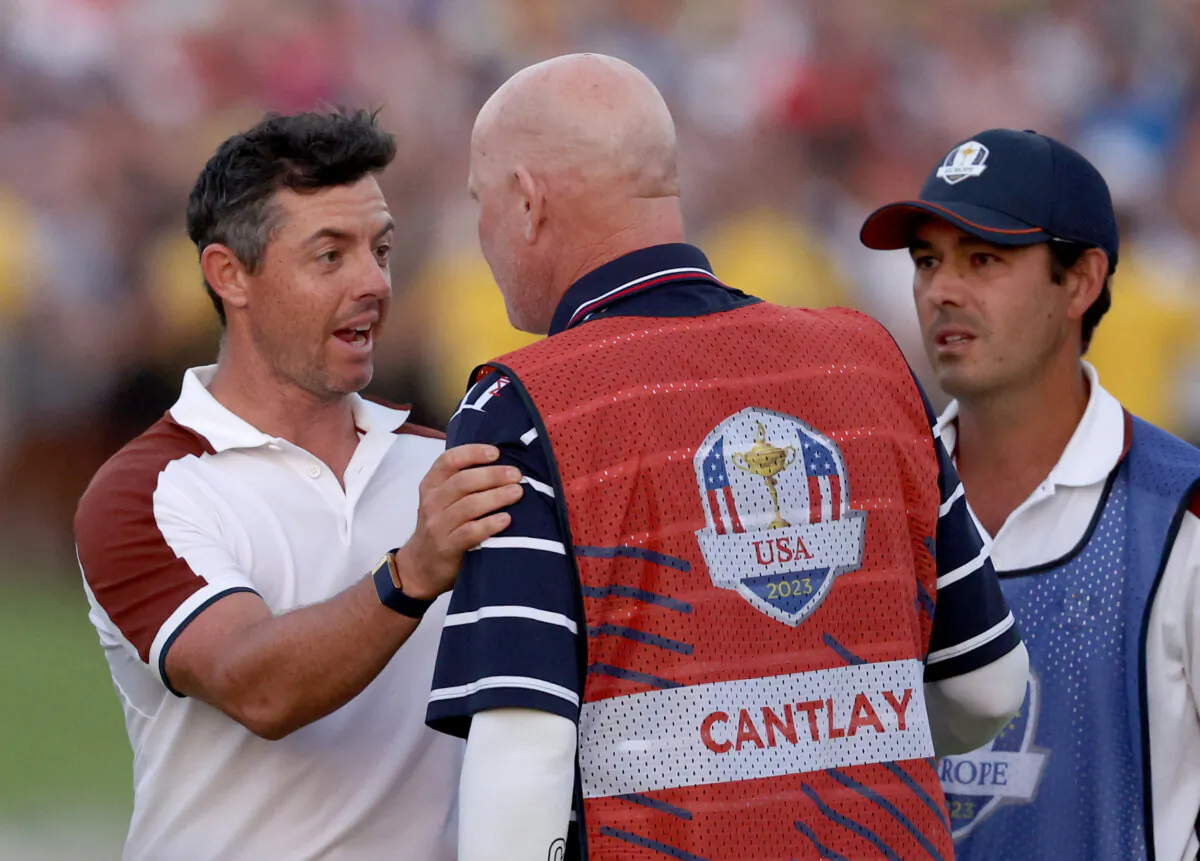 Rory McIlroy of Team Europe speaks with caddie of Patrick Cantlay of Team United States (not pictured), Joe LaCava on the 18th green during the Saturday afternoon fourball matches of the 2023 Ryder Cup at Marco Simone Golf Club in Rome on Sept. 30, 2023. (Patrick Smith/Getty Images)