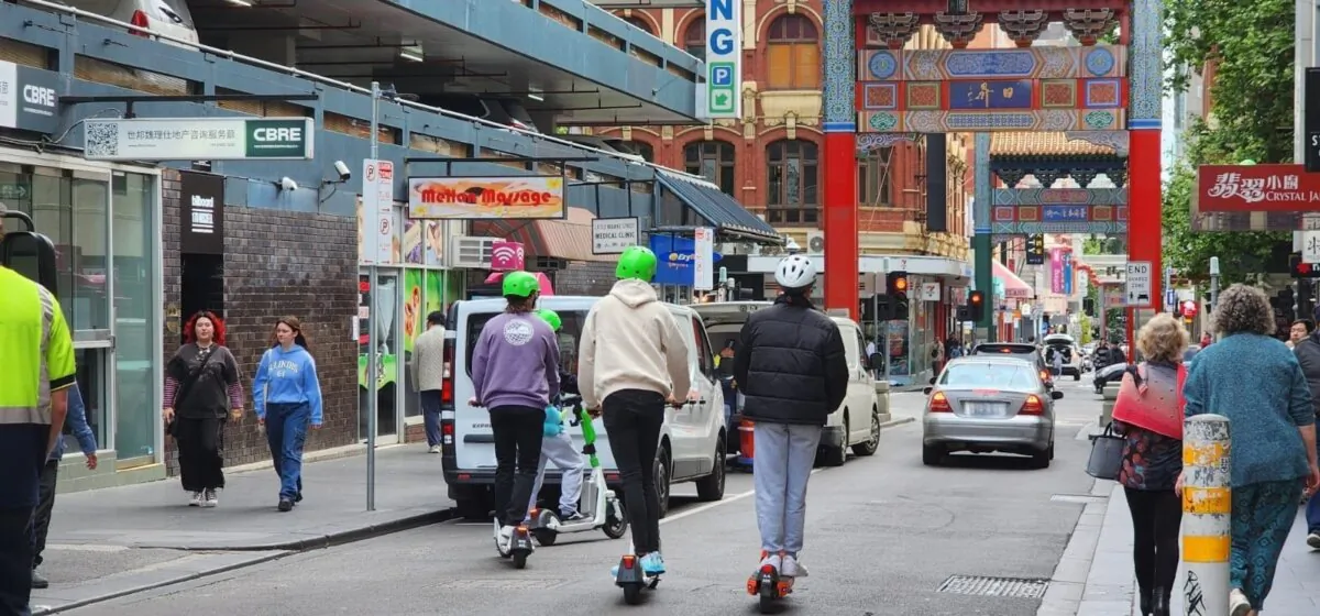 Three young people ride e scooters towards China town in Melbourne, Australia, on Oct. 28, 2023. (Susan Mortimer/The Epoch Times)