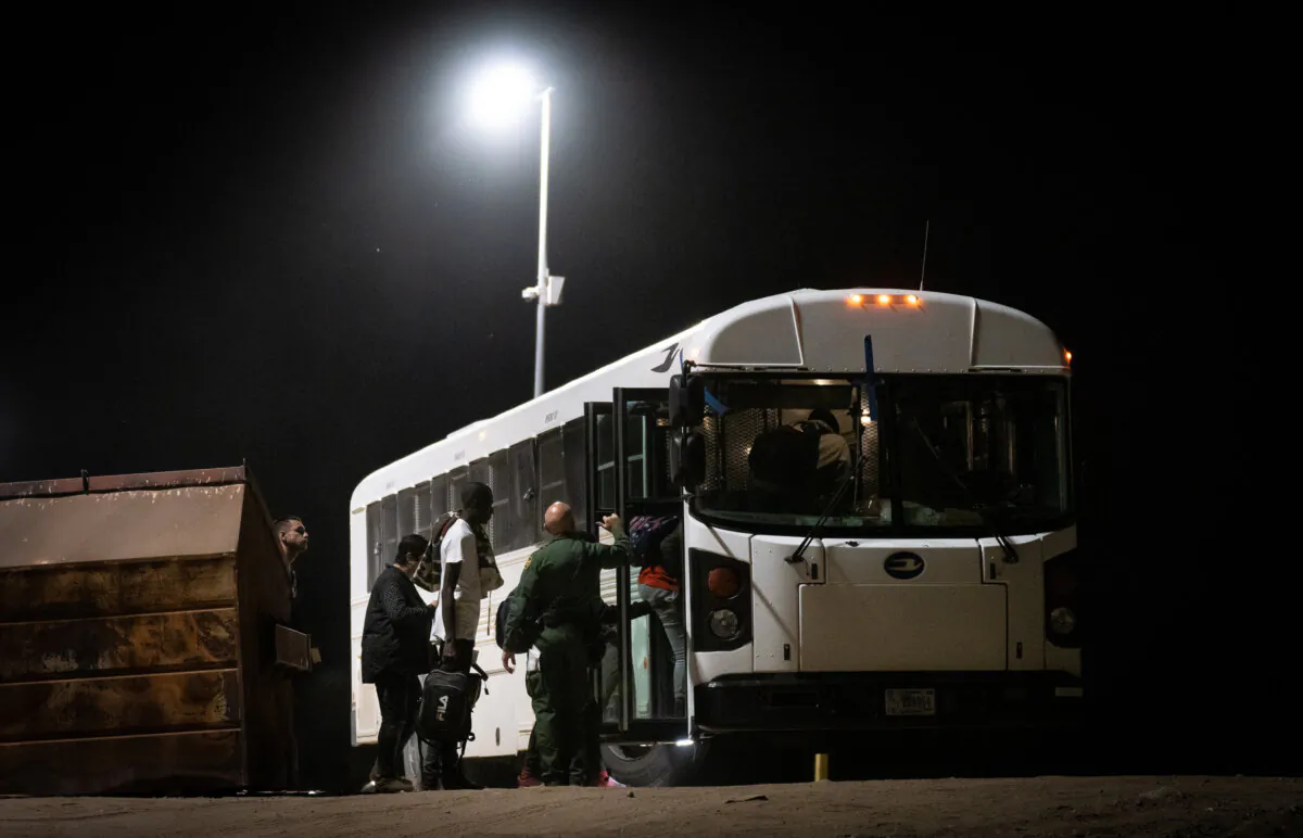 Migrants prepare to be transported by bus to processing faciities in Yuma, Ariz., on May 18, 2023. (John Fredricks/The Epoch Times