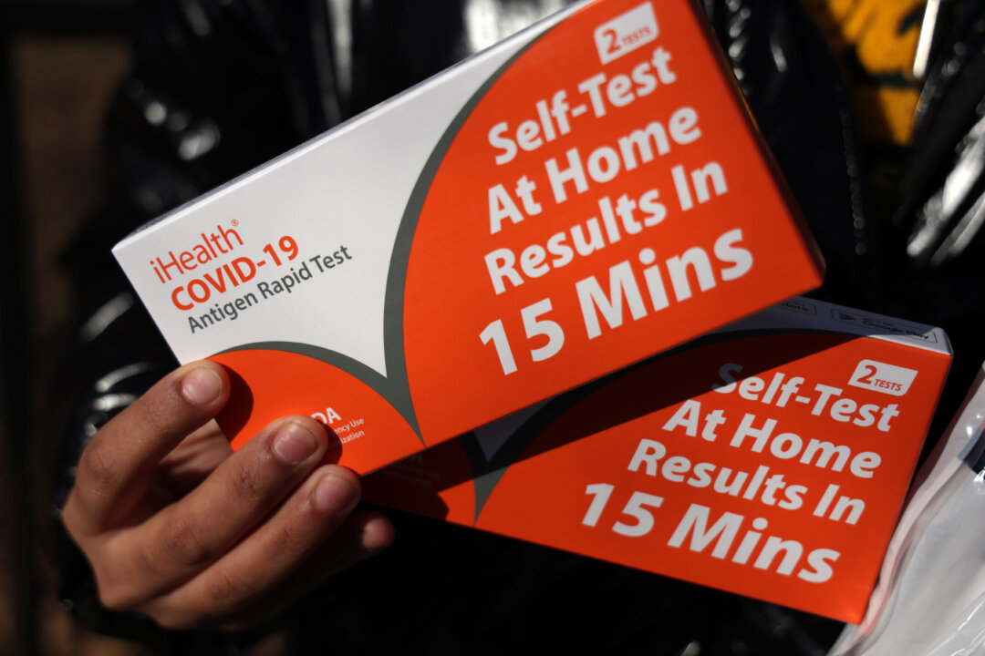 A woman shows the free COVID test kits he has received outside Petworth Library in the District of Columbia, on Dec. 23, 2021. (Alex Wong/Getty Images)