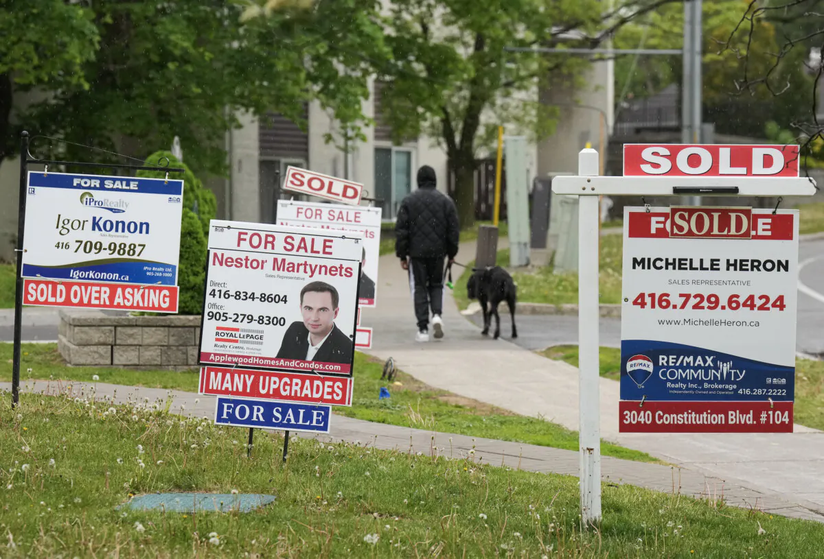 A person walks past multiple for-sale and sold real estate signs in Mississauga, Ont., on May 24, 2023. (Nathan Denette/The Canadian Press)