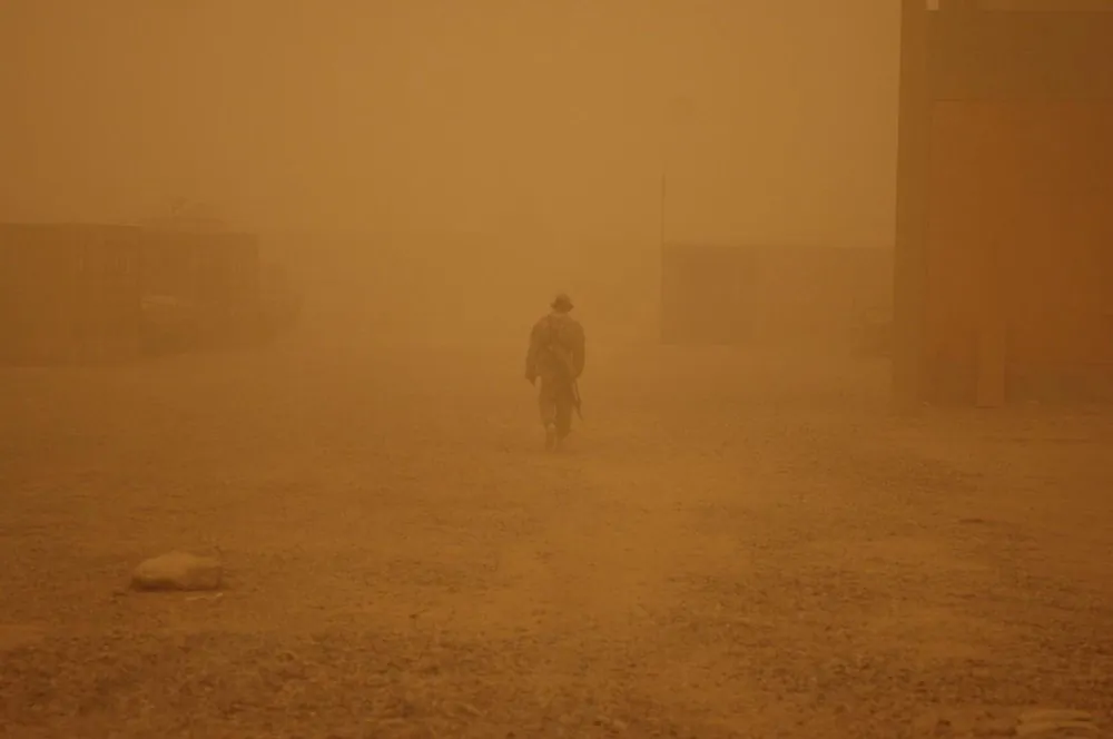 A lone soldier walks through a fog of sand covering Camp Striker and much of the Baghdad area in Iraq, circa 2005. (48th Infantry Brigade Combat Team, U.S. Army)