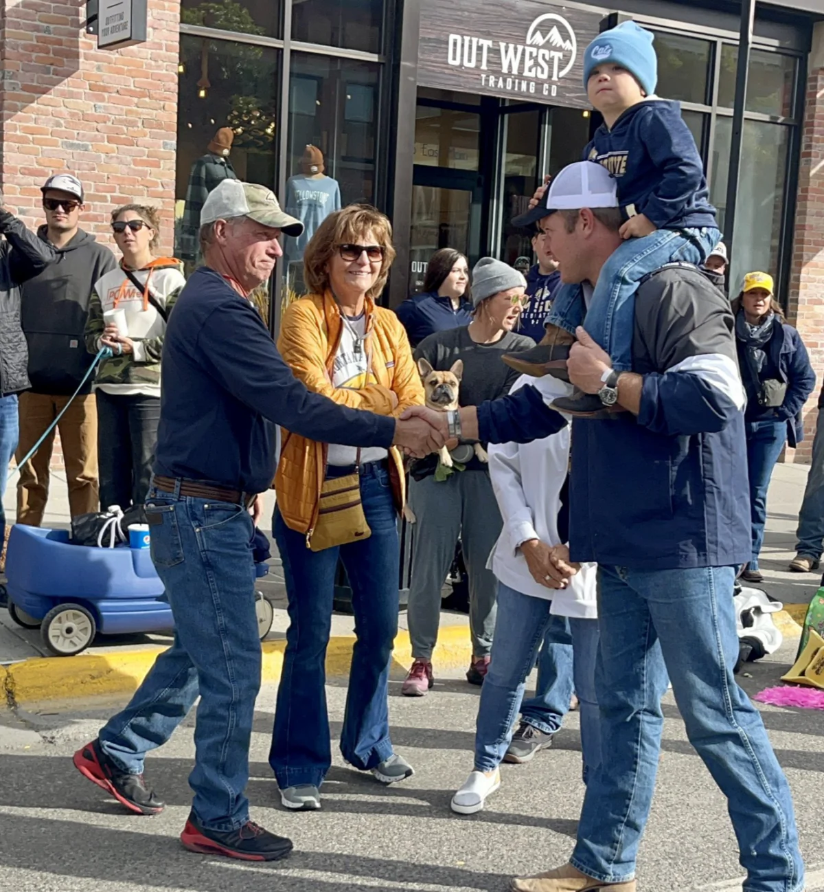 Montana Republican U.S. Senate candidate Tim Sheehy, with one of his sons on his shoulders, greets people along Montana State University’s Homecoming Parade route in October 2023 in Bozeman. (Tim Sheehy for Montana)