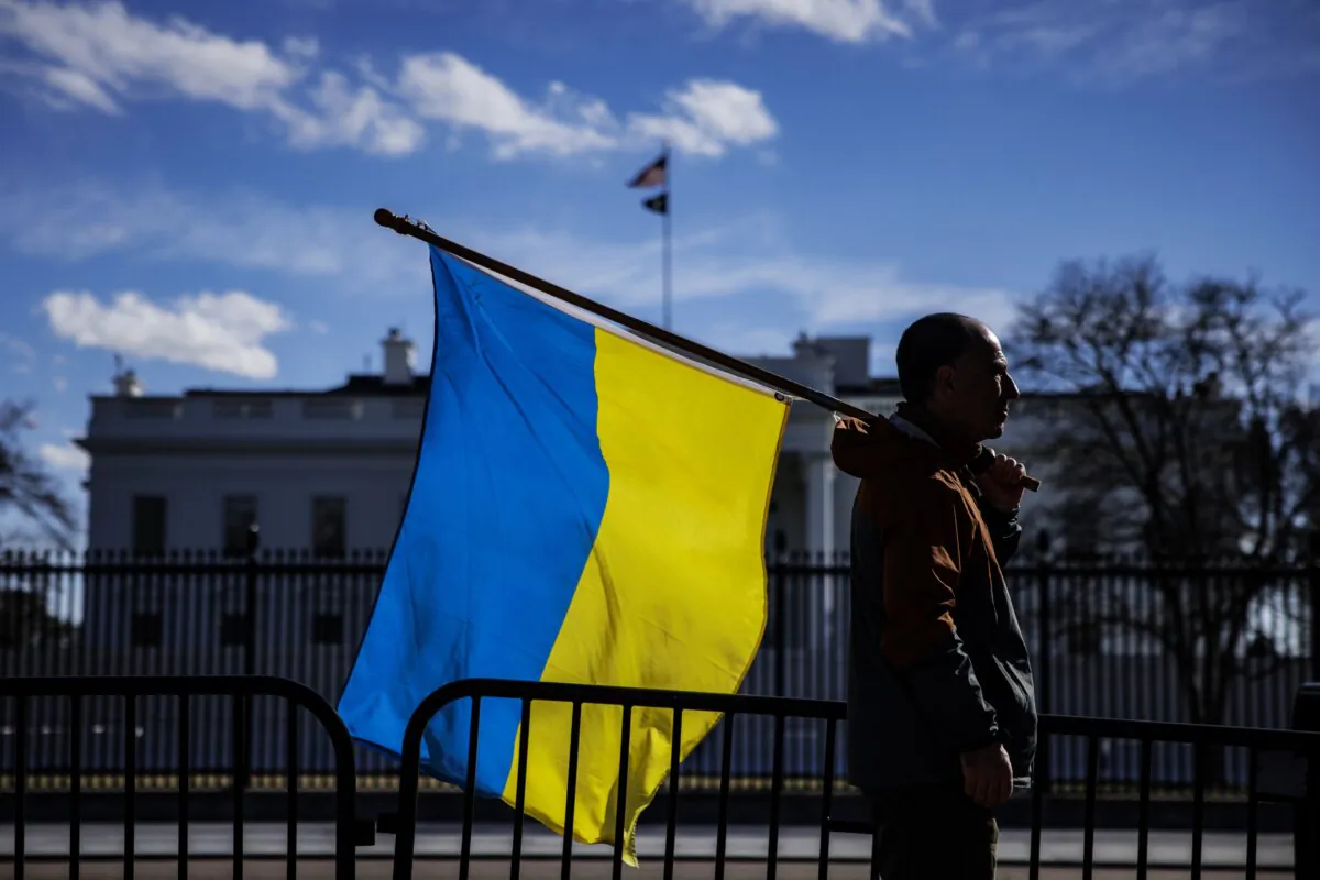 A man with a Ukrainian flag stands on Pennsylvania Avenue in front of the White House as demonstrators gather to protest the Russian invasion in Washington, DC on Feb. 25, 2022. (Samuel Corum/Getty Images)