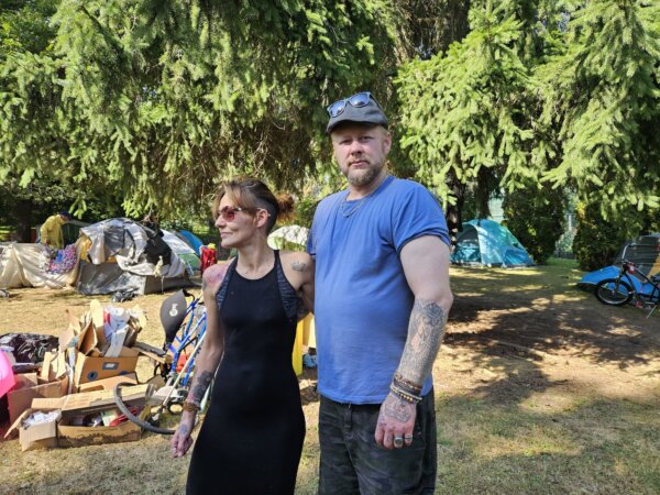 Virginia Bailey and Chris Kneilands, residents of an encampment on King Street in Cobourg, Ont., pose near their tent on Oct. 2, 2023. (Tara MacIsaac/The Epoch Times)