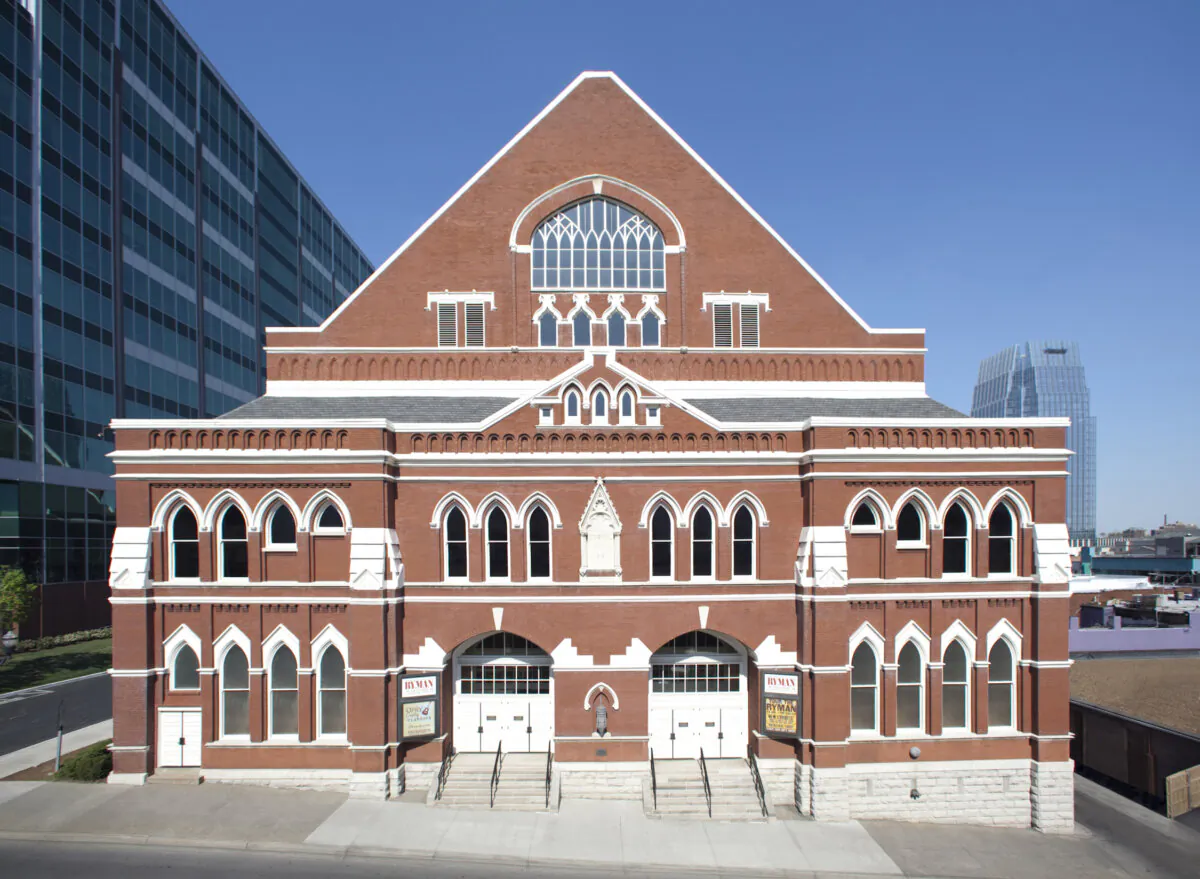 Situated among skyscrapers and modern all-glass buildings, Ryman Auditorium stands out with its red brick facade and Victorian Gothic Revival adornments. Pointed arched windows, classical pediment elements, and a centerpiece tracery window (divided into ornamental sections) at the top, capped triangular portion set the auditorium apart from the rest of the neighborhood. (Courtesy of Deena Bouknight)
