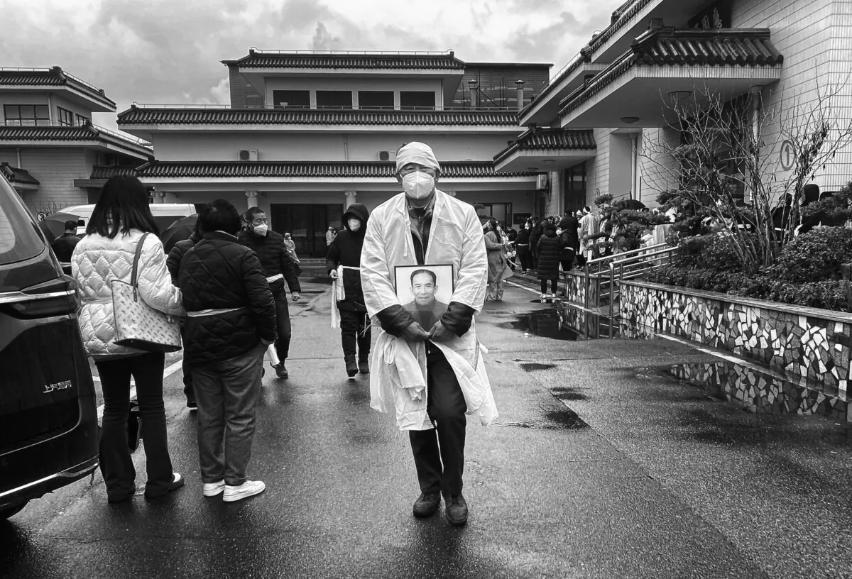 A mourner carries a photo of a loved one as he wears traditional white funeral clothing at a funeral home in Shanghai, China, on Jan. 14, 2023. (Kevin Frayer/Getty Images)