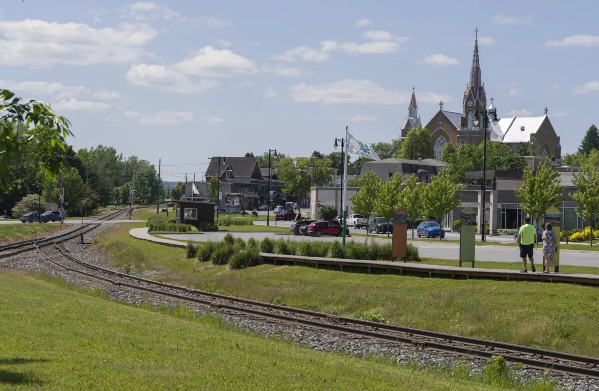 People walk on the boardwalk built along the crash site of a train derailment in Lac-Mégantic, Que., on June 22, 2023. (The Canadian Press/Christinne Muschi)