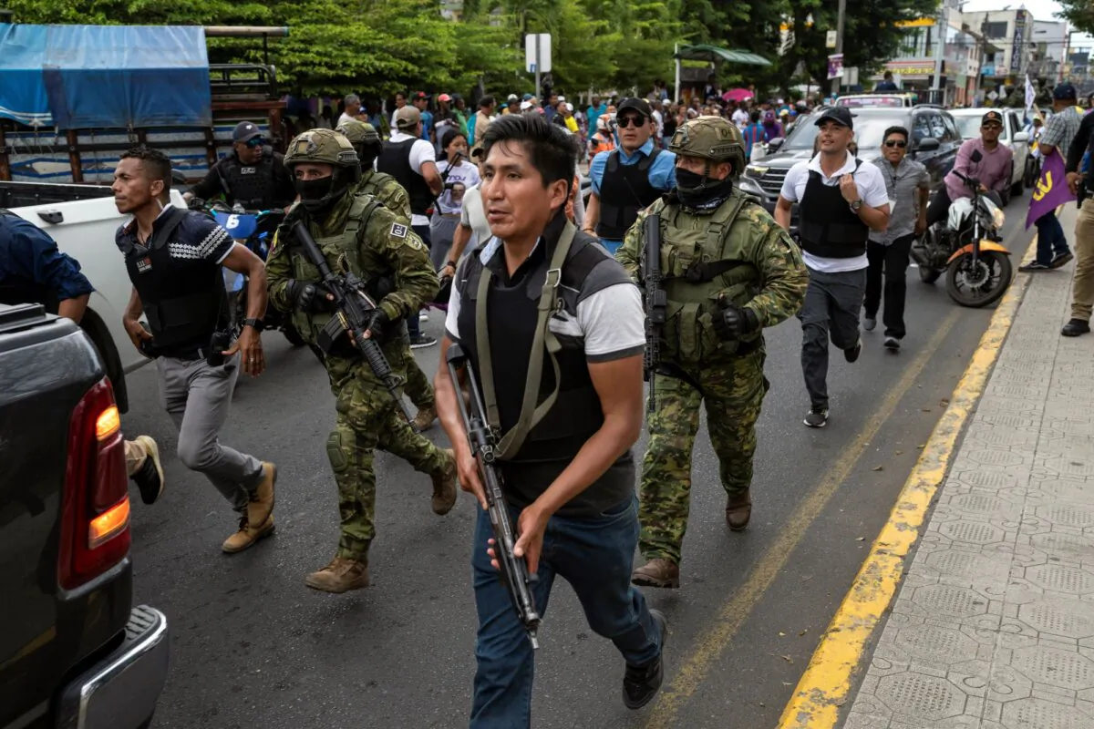 Soldiers and police provide security behind an armored vehicle as supporters of presidential candidate Daniel Noboa, of the National Democratic Action Alliance political party, attend a rally with their candidate in downtown Esmeraldas, Ecuador, on Oct. 6, 2023. (Rodrigo Abd/AP)