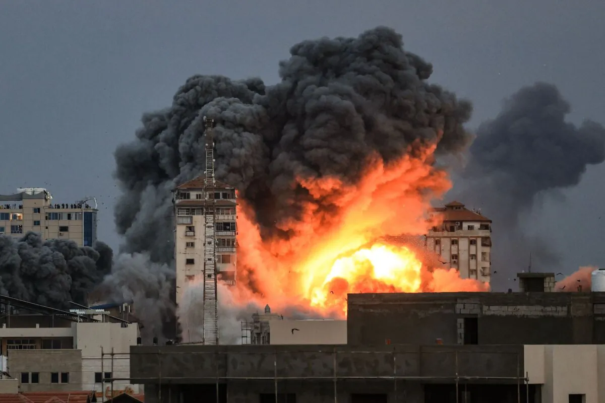 People standing on a rooftop watch as Israel strikes the "Palestine Tower building,” which the IDF says was used by a number of Hamas units, including intelligence, weapon production, and offices of senior members, in Gaza City on Oct. 7, 2023. (Mahmud Hams/AFP via Getty Images)