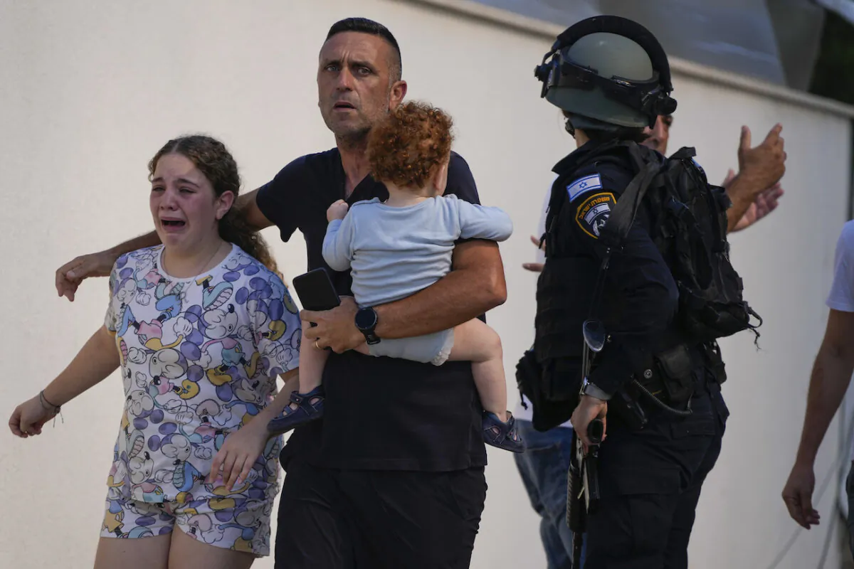 Israeli police officers evacuate a family from a site hit by a rocket fired from the Gaza Strip, in Ashkelon, southern Israel, on Oct. 7, 2023. (AP Photo/Tsafrir Abayov)