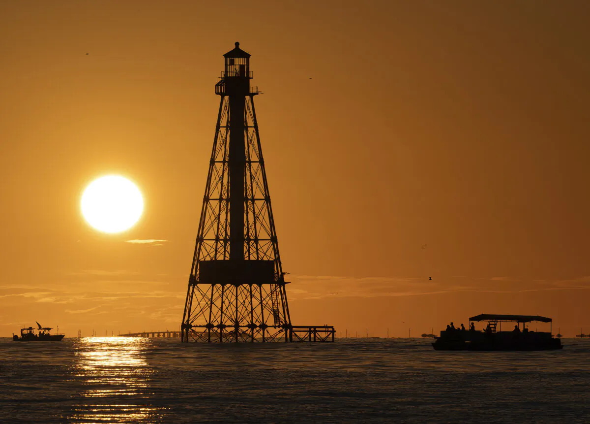 Boaters watch a sunset behind Alligator Reef Lighthouse in the Florida Keys off Islamorada, Fla., on Oct. 6, 2023. (Andy Newman/Florida Keys News Bureau via AP)