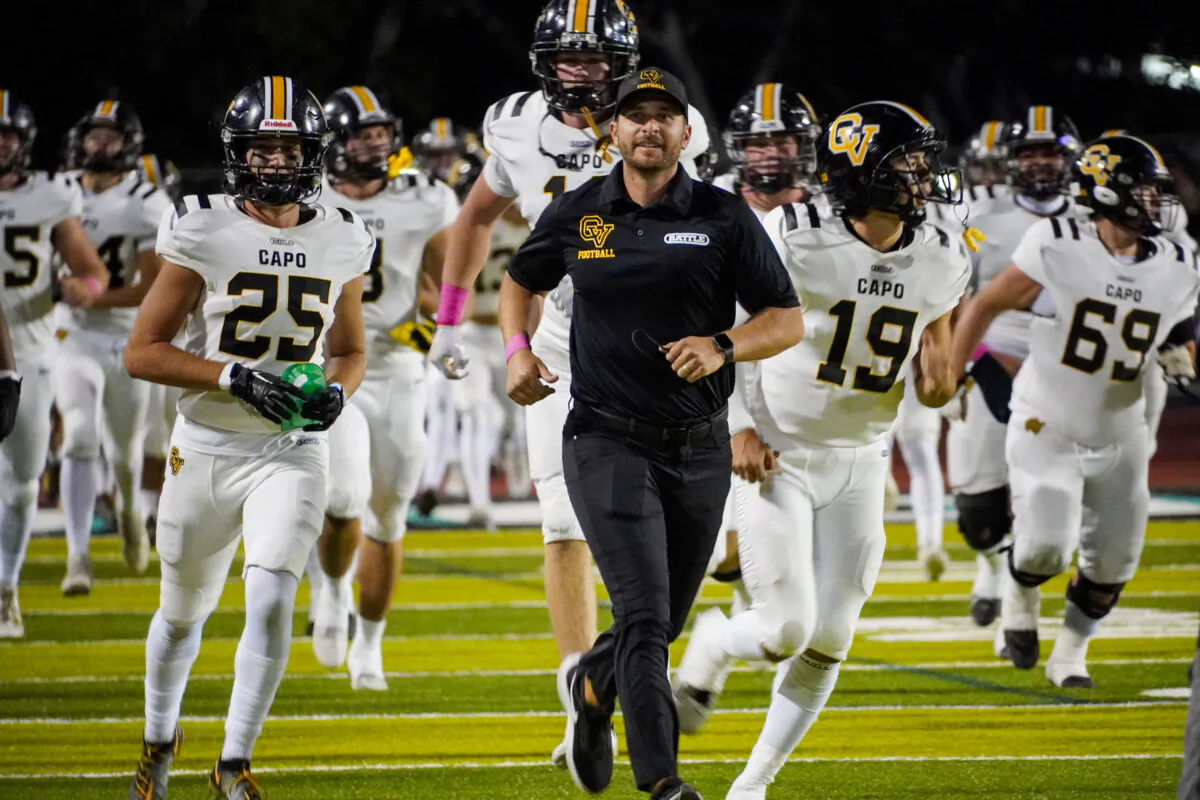 Capistrano Valley High School Football Coach Sean Curtis leads the team onto the field, with No. 19, junior quarterback Tommy Acosta, to the right, in Aliso Viejo, Calif., on Oct. 6, 2023. (Courtesy of Monica Acosta)