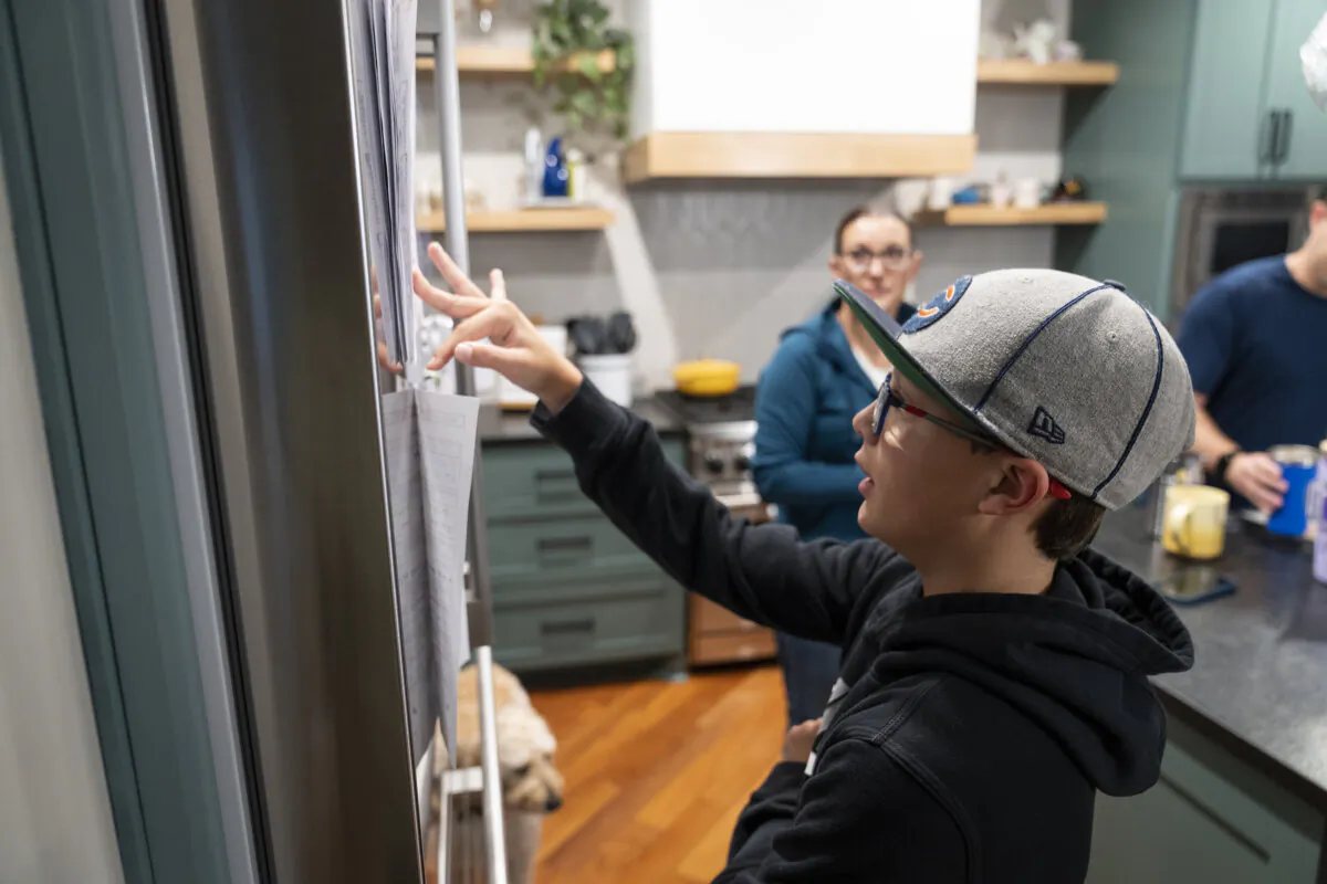Twin Cities Instagrammer/organizing expert/author Jessica Litman's 11-year-old son Eli checks the printout on the fridge for the school lunch menu as they get ready in the morning at home in Maple Grove, Minnesota, on Sept. 26, 2023. (Leila Navidi/Minneapolis Star Tribune/TNS)