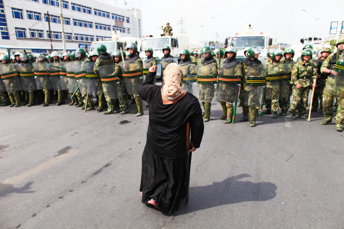 An Uyghur woman protests in front of policemen on a street in Urumqi, the capital of Xinjiang, on July 7, 2009. (Guang Niu/Getty Images)