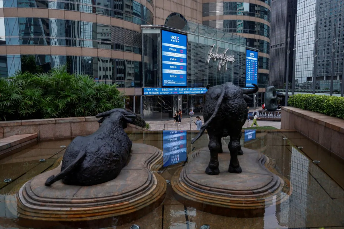 Bull statues are placed in front of screens showing the Hang Seng stock index and stock prices outside Exchange Square, in Hong Kong on Aug. 18, 2023. (Tyrone Siu/Reuters)