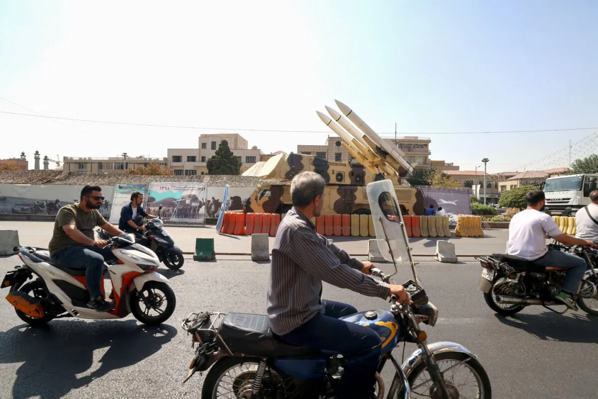 Motorcyclists pass an Iranian medium range air defense missile system displayed on a main road as part of a street exhibition in Tehran, Iran, on Sept. 27, 2023. (Atta Kenare/AFP via Getty Images)