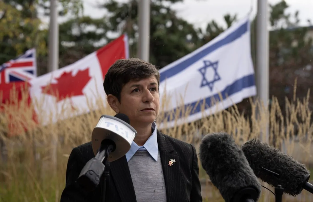 The flags of Ontario, Canada and Israel fly at half mast as Jewish Federation of Ottawa CEO Andrea Freedman reads a statement in Ottawa from the family of Adi Vital-Kaploun who was killed by Hamas, on Oct. 11, 2023. (The  Canadian Press/Adrian Wyld)