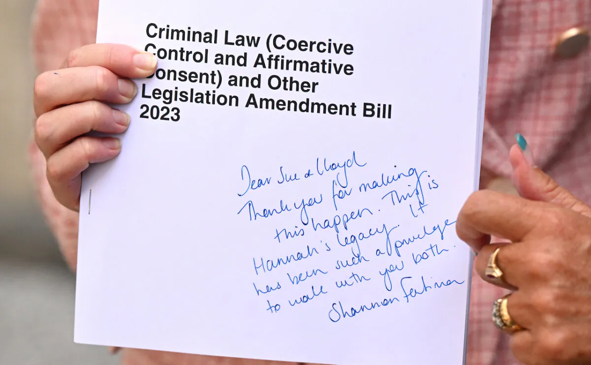 Queensland Minister for Health, Mental Health and Ambulance Services and Minister for Women, Shannon Fentiman is seen holding a copy of the legislation with a hand written note to Sue and Lloyd Clarke, parents of domestic violence murder victim Hannah Clarke at Parliament House in Brisbane, Australia on Oct. 11, 2023. The Queensland government has introduced laws into parliament to criminalise coercive control which will carry a maximum penalty of 14 years in jail. (AAP Image/Darren England)