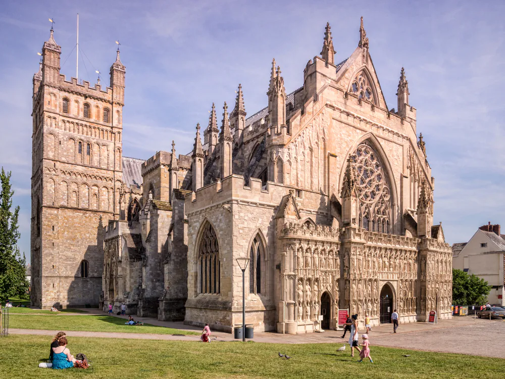 Located in Devon, England, Exeter Cathedral displays a stone facade extensively decorated with carved sculptures, flying buttresses, pointed arches, and large windows, which allow in light. Two Romanesque square towers on the left of front facade date from the Norman cathedral that previously stood on the site. (travellight/Shutterstock)