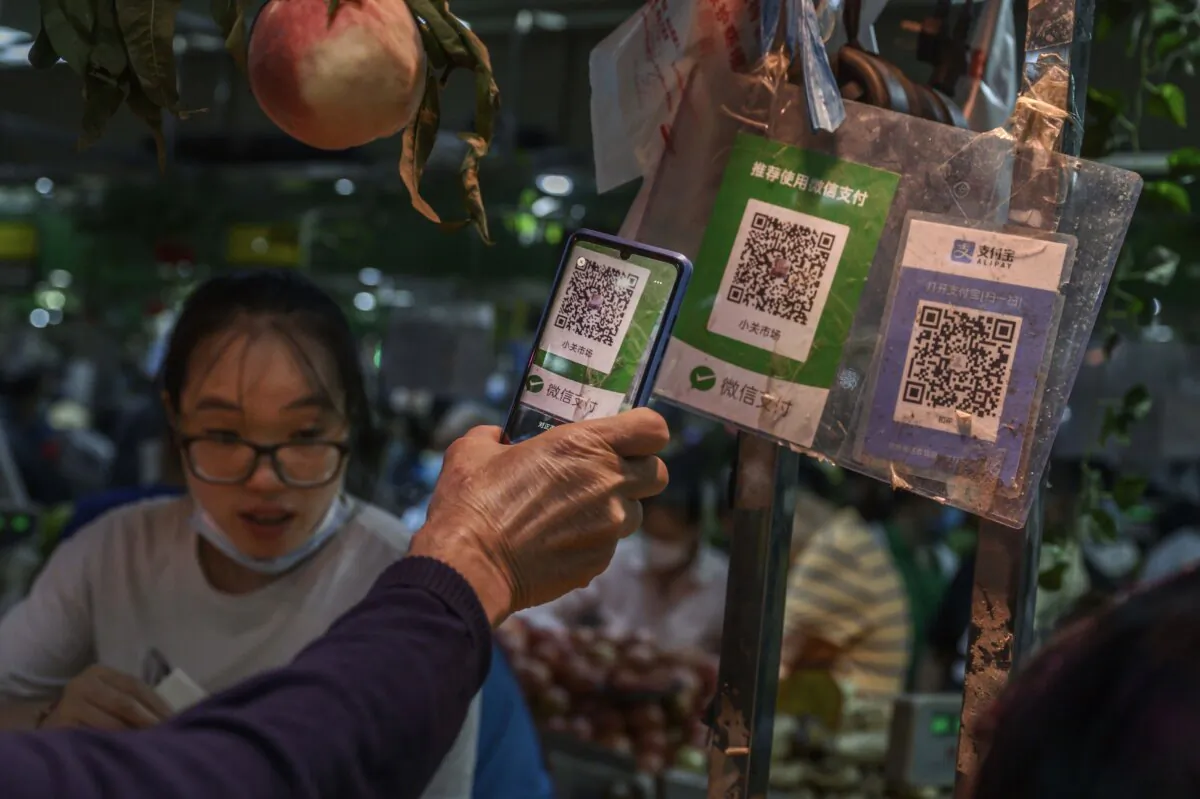 A Chinese customer uses his mobile to pay via a QR code with the We Chat app at a local market on September 19, 2020 in Beijing, China. (Photo by Kevin Frayer/Getty Images)