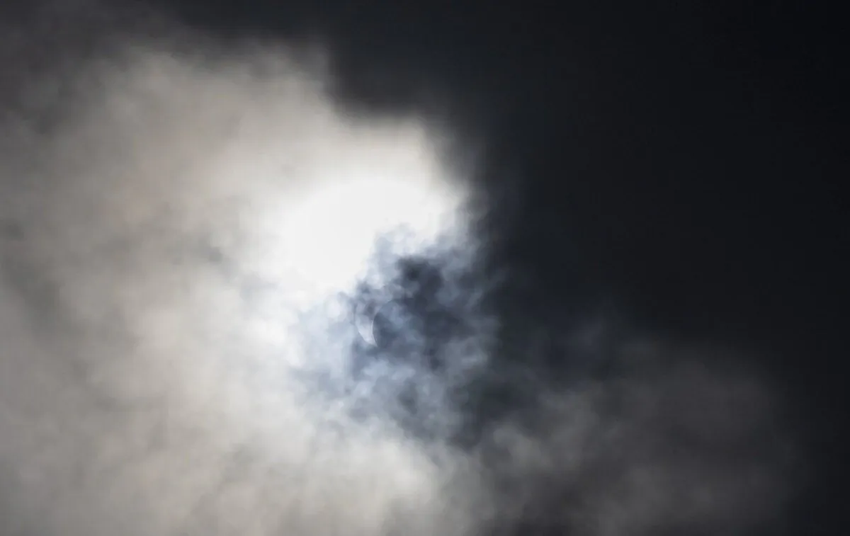 A partial solar eclipse is seen through the clouds from the Frost Science Museum, in Miami, Oct. 14, 2023. (The Canadian Press/AP-Miami Herald, Matias J. Ocner)