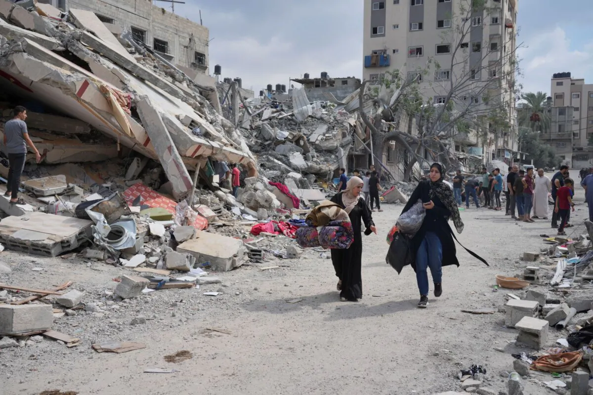 Palestinian women walk by buildings destroyed in airstrikes in Nuseirat camp in the central Gaza Strip, on Oct. 16, 2023. (Hatem Moussa/AP)