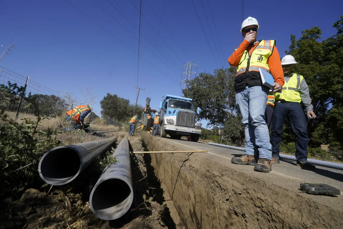 (L-R) Paul Standen, senior director of underground regional delivery and project manager Jeremy Schanaker look on during a tour of a Pacific Gas and Electric crew burying power lines in Vacaville, Calif., on Oct. 11, 2023. (Jeff Chiu/AP Photo)