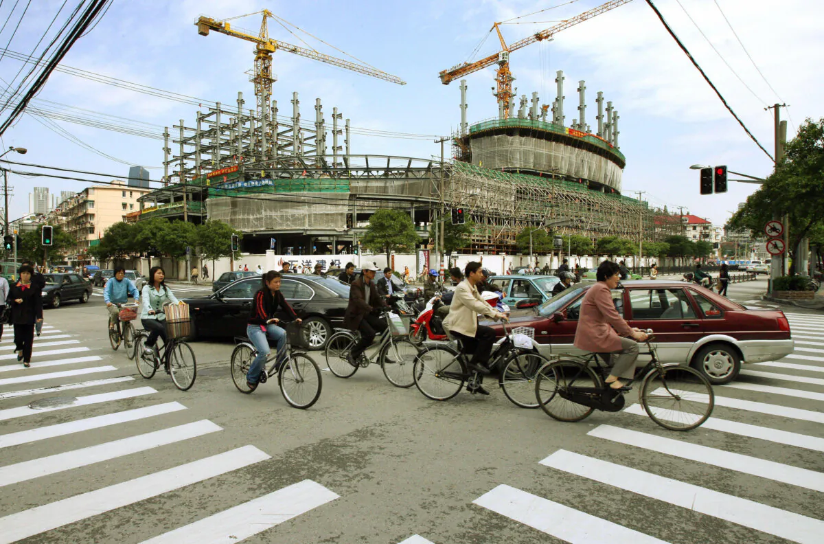 Early morning traffic passes in front of a large property development under construction in Shanghai on May 19, 2006. (Mark Ralston/AFP via Getty Images)