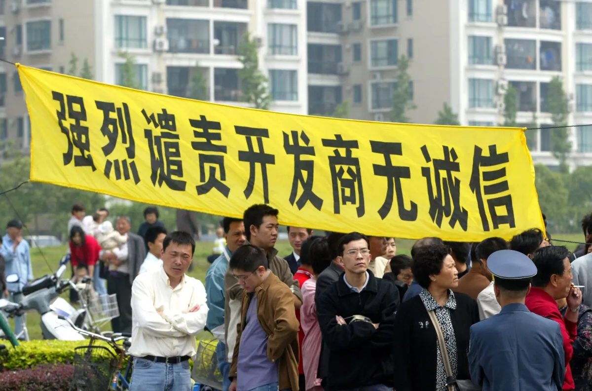 Homeowners hang a banner that reads, "Strongly condemn the dishonest real estate developer," to protest at the Shanghai Cannes Residential Area, in Shanghai on May 14, 2006. (China Photos/Getty Images)