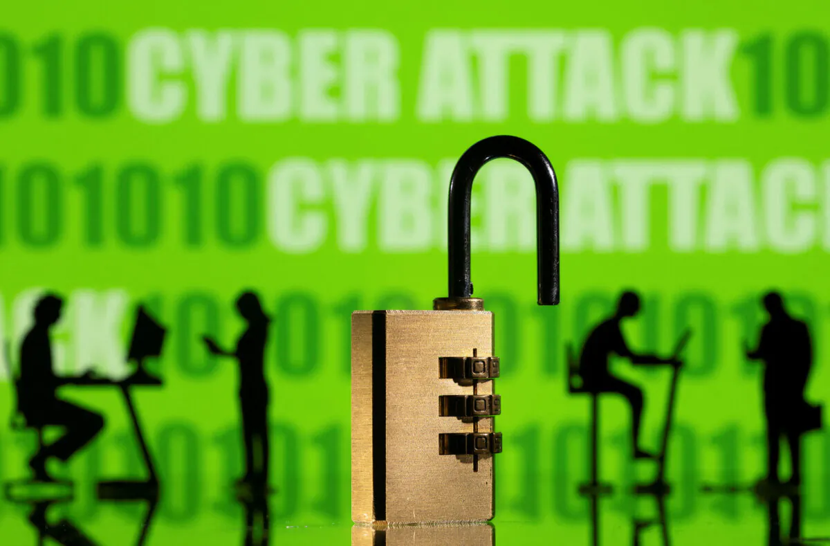 3D printed models of people working on computers and padlock in front of a displayed CYBER ATTACK words and binary code in a picture illustration taken on Feb. 1, 2022. (Dado Ruvic/Illustration/Reuters)