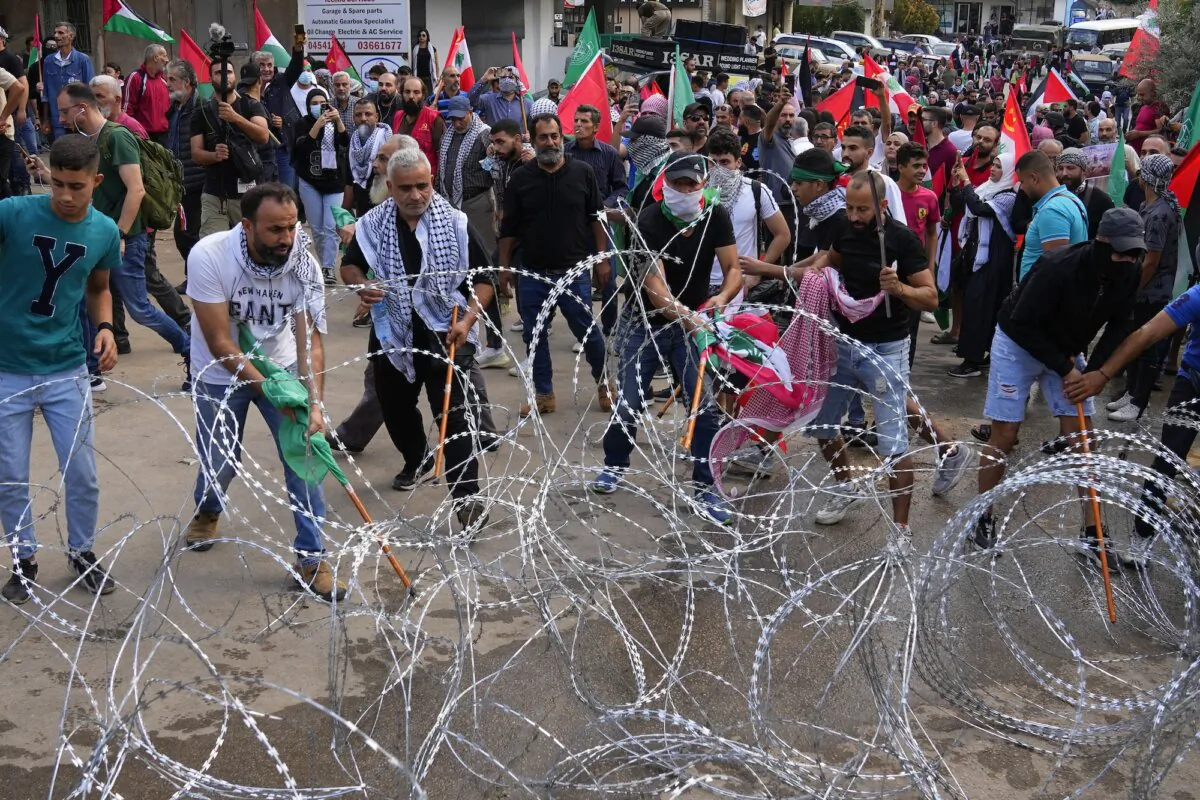 Protesters try to remove barbed wires that block a road leading to the U.S. embassy, during a demonstration in Beirut, Lebanon, on Oct. 18, 2023. (AP Photo/Bilal Hussein)