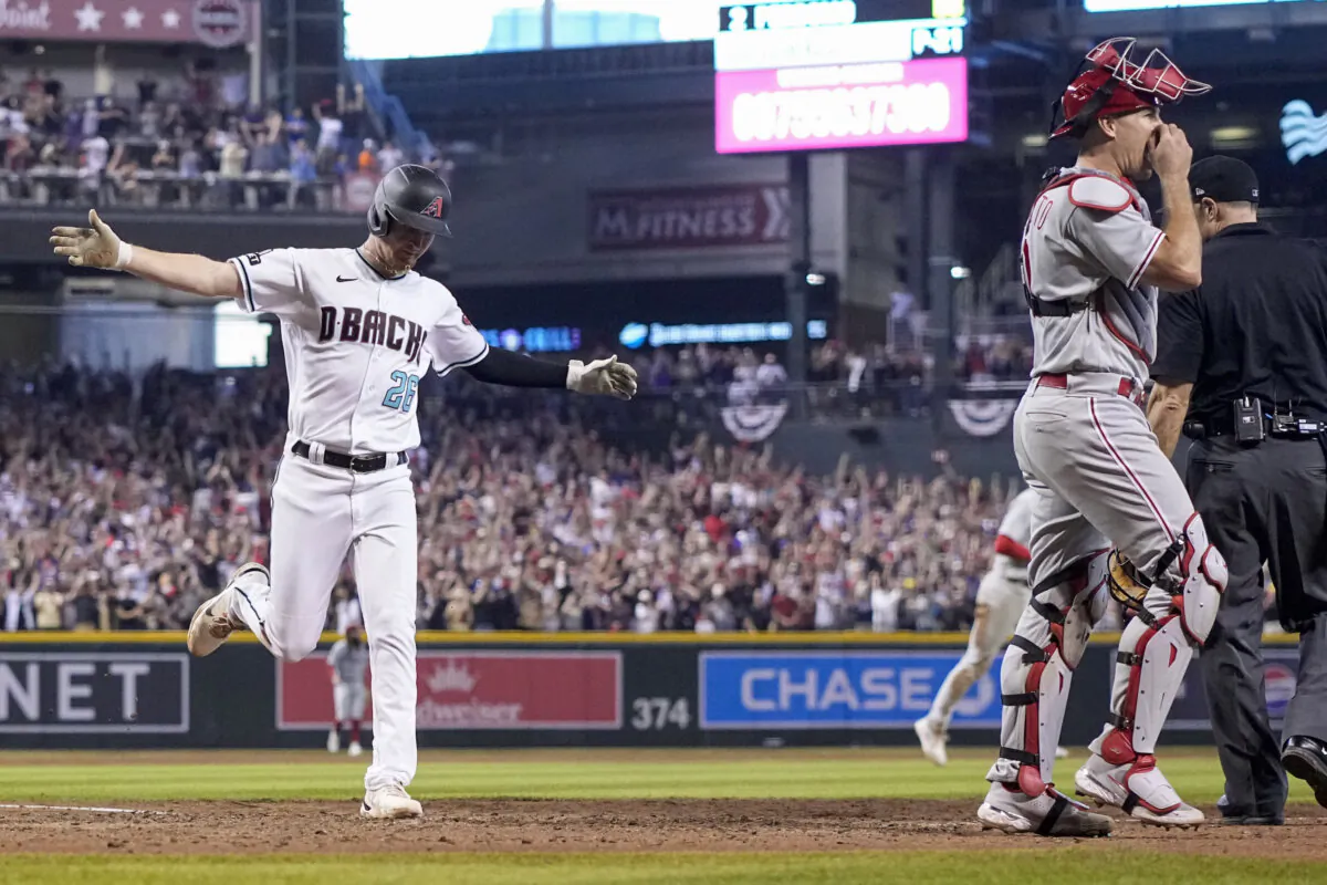 Arizona Diamondbacks' Pavin Smith celebrates after scoring the game winning run past Philadelphia Phillies catcher J.T. Realmuto on a single by Ketel Marte during the ninth inning in Game 3 of the NLCS in Phoenix on Oct. 19, 2023. (Brynn Anderson/AP Photo)