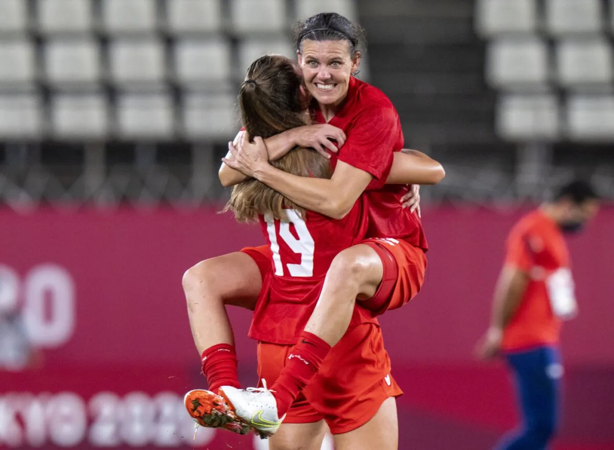 Canada forward Christine Sinclair (12) leaps into the arms of forward Jordyn Huitema (19) to celebrate their win in semifinal football action against the United States of America at the Tokyo Olympics in Kashima, Japan, on Aug. 2, 2020. (The Canadian Press/Frank Gunn)