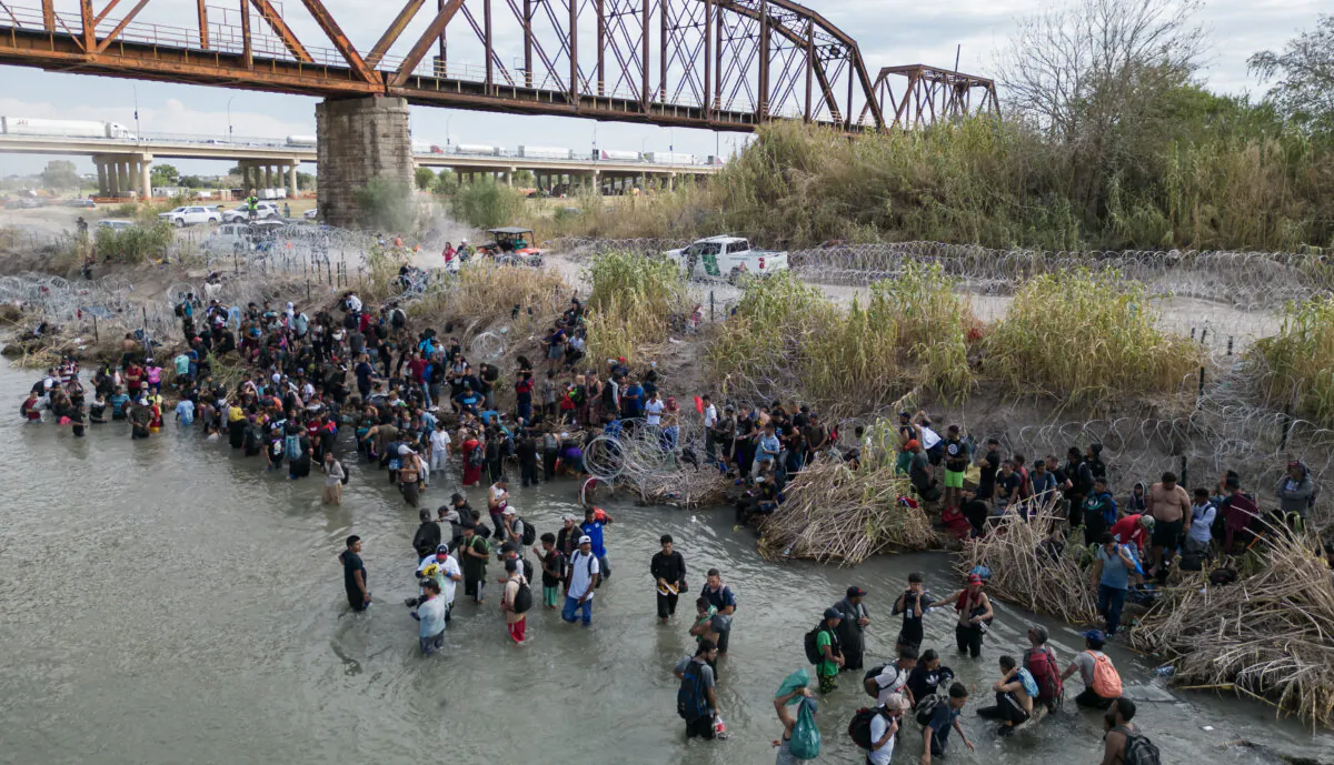 People wait in the Rio Grande for an opening in the razor wire barrier, to illegally cross into the United States at Eagle Pass, Texas, on Sept. 25, 2023. (Andrew Caballero-Reynolds/AFP via Getty Images)