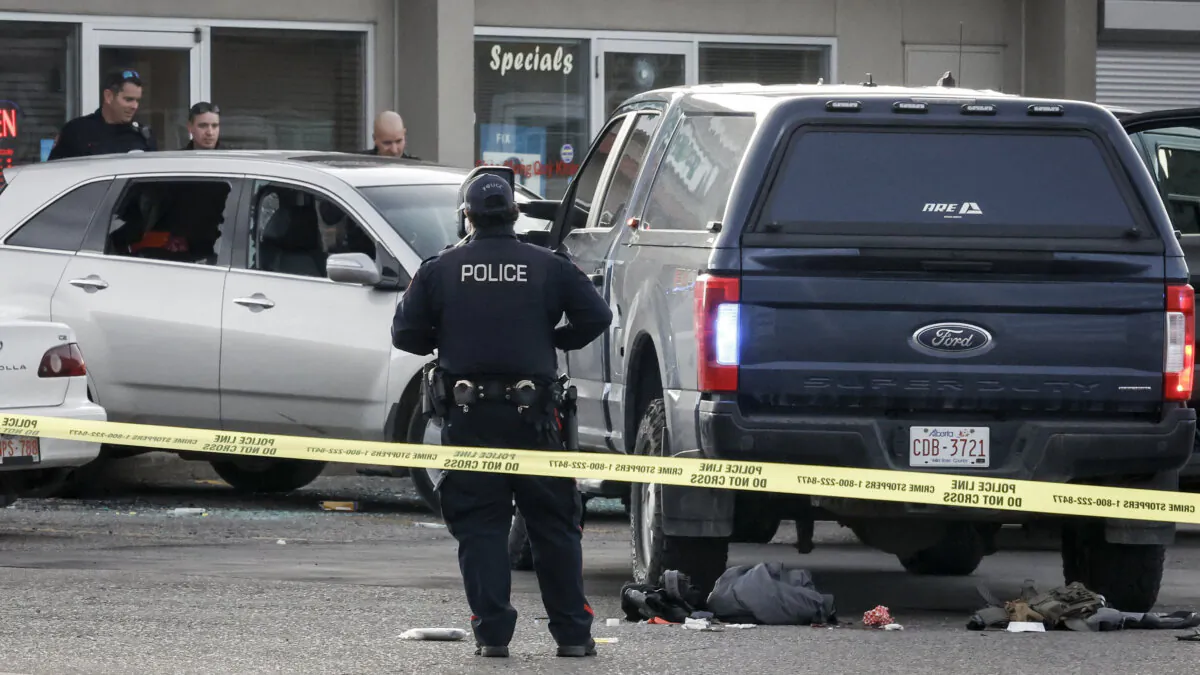 Calgary Police Service officers examine a bullet-riddled car at the scene where a colleague was shot and injured and a suspect was killed, in Calgary on Oct. 18, 2023. (The Canadian Press/Jeff McIntosh)