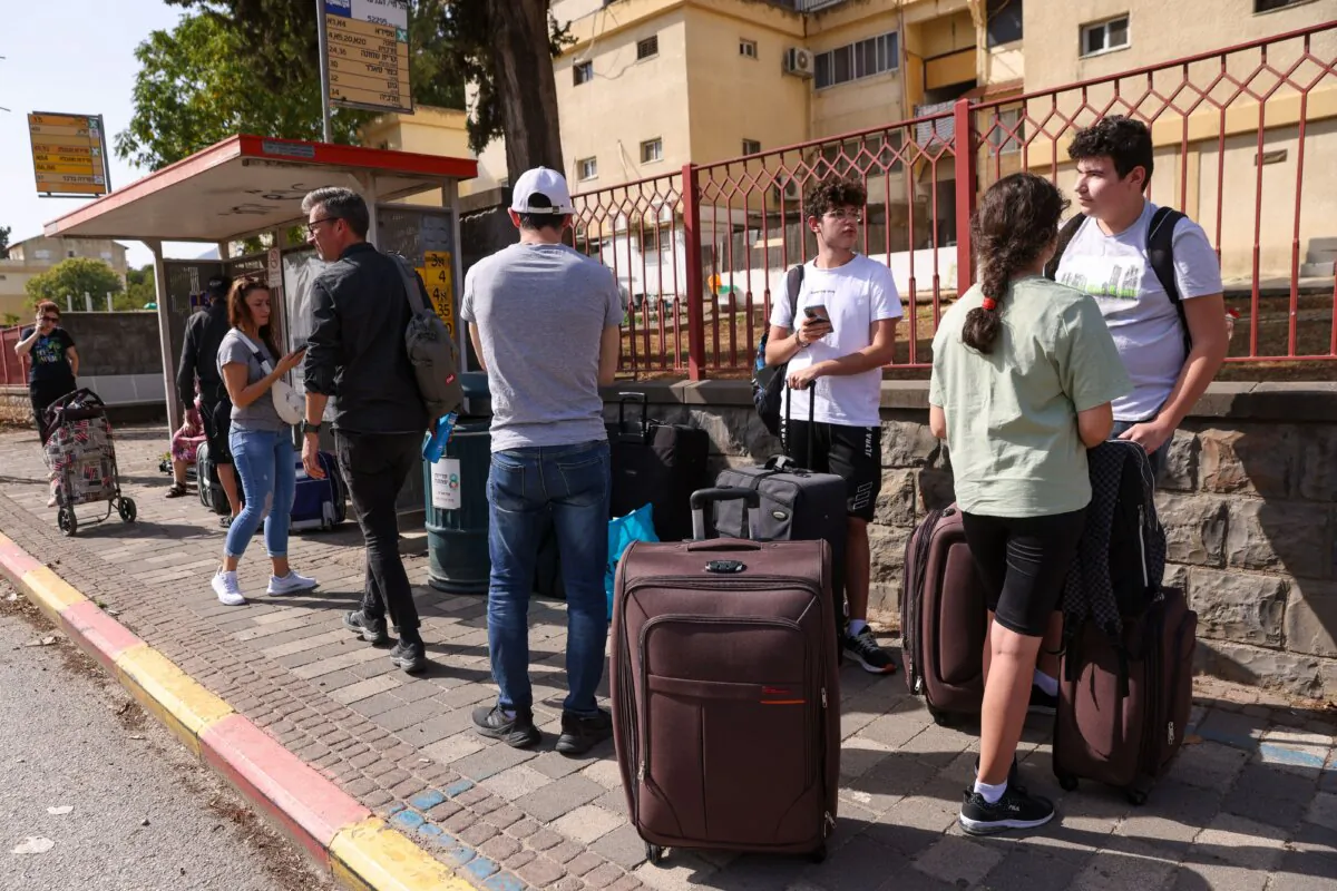 People with their luggage wait at a bus stop in the northern Israeli town of Kiryat Shmona to be evacuated to a safer location, on Oct. 22, 2023. (Jalaa Marey/AFP via Getty Images)