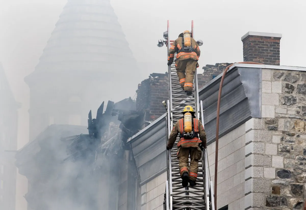 Firefighters climb a ladder at the scene of a fire in Old Montreal, on March 16, 2023. (The Canadian Press/Graham Hughes)