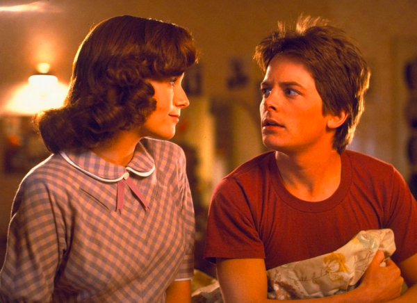 girl and boy sit on bed in BACK TO THE FUTURE