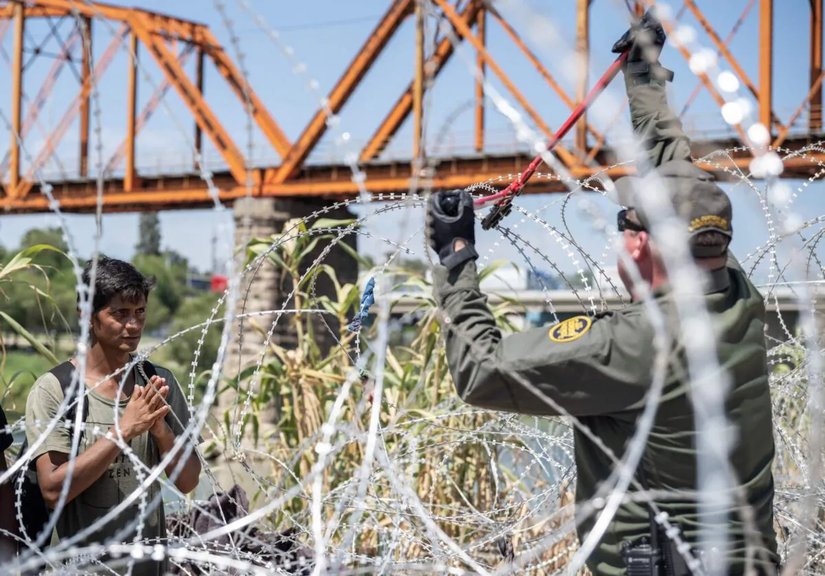 A migrant from Venezuela waits for a U.S. Border Patrol agent to cut the razor wire after he crossed the Rio Grande to Eagle Pass, Texas, on Sept. 24, 2023. (Andrew Caballero-Reynolds/AFP via Getty Images)