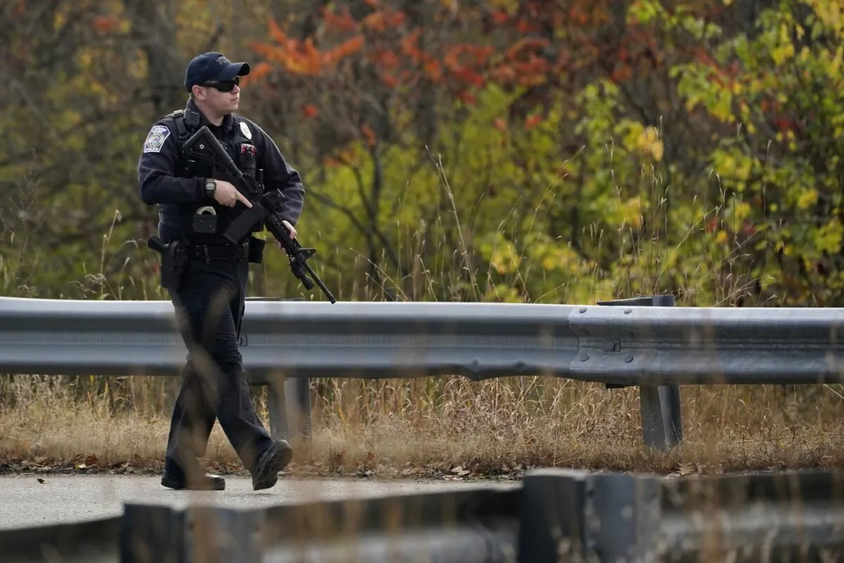 A police officer walks along a rural road during a manhunt for the suspect of Wednesday's mass shootings  in Lisbon, Maine, on Oct. 26, 2023. (The Canadian Press/AP-Robert F. Bukaty)