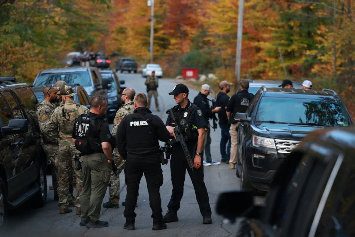 Law enforcement officials gather in the road leading to the home of the suspect being sought in connection with two mass shootings in Bowdoin, Maine, on Oct. 26, 2023. (Joe Raedle/Getty Images)