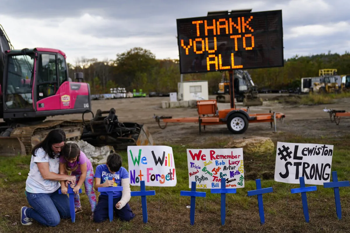 Bre Allard, accompanied by her children Lucy, 5, and Zeke, 8, plant crosses in honor of the victims of this week's mass shooting in Lewiston, Maine, on Oct. 28, 2023. (Matt Rourke/AP Photo)