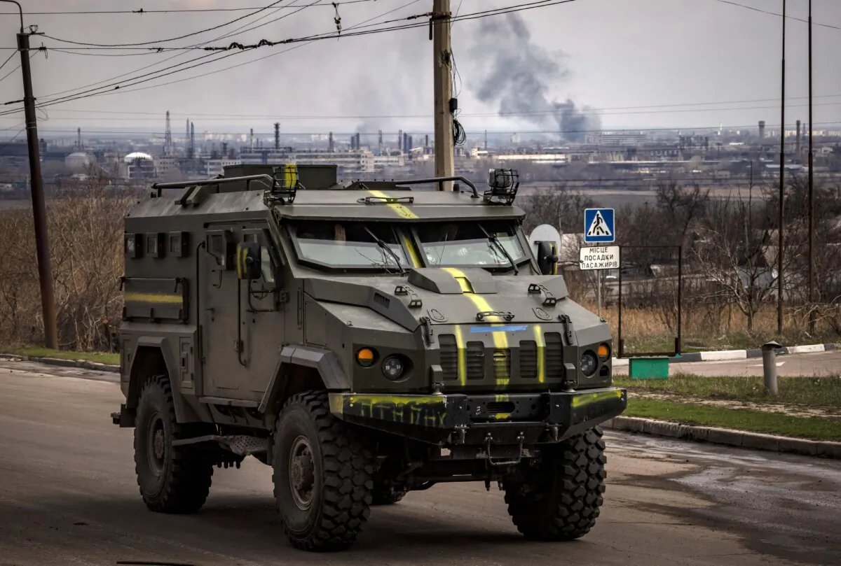 A Ukrainian army armored vehicle passes on a road as smoke rises in the background in the city of Severodonetsk, Donbass region, Ukraine, on April 6, 2022. (Fadel Senna/AFP via Getty Images)
