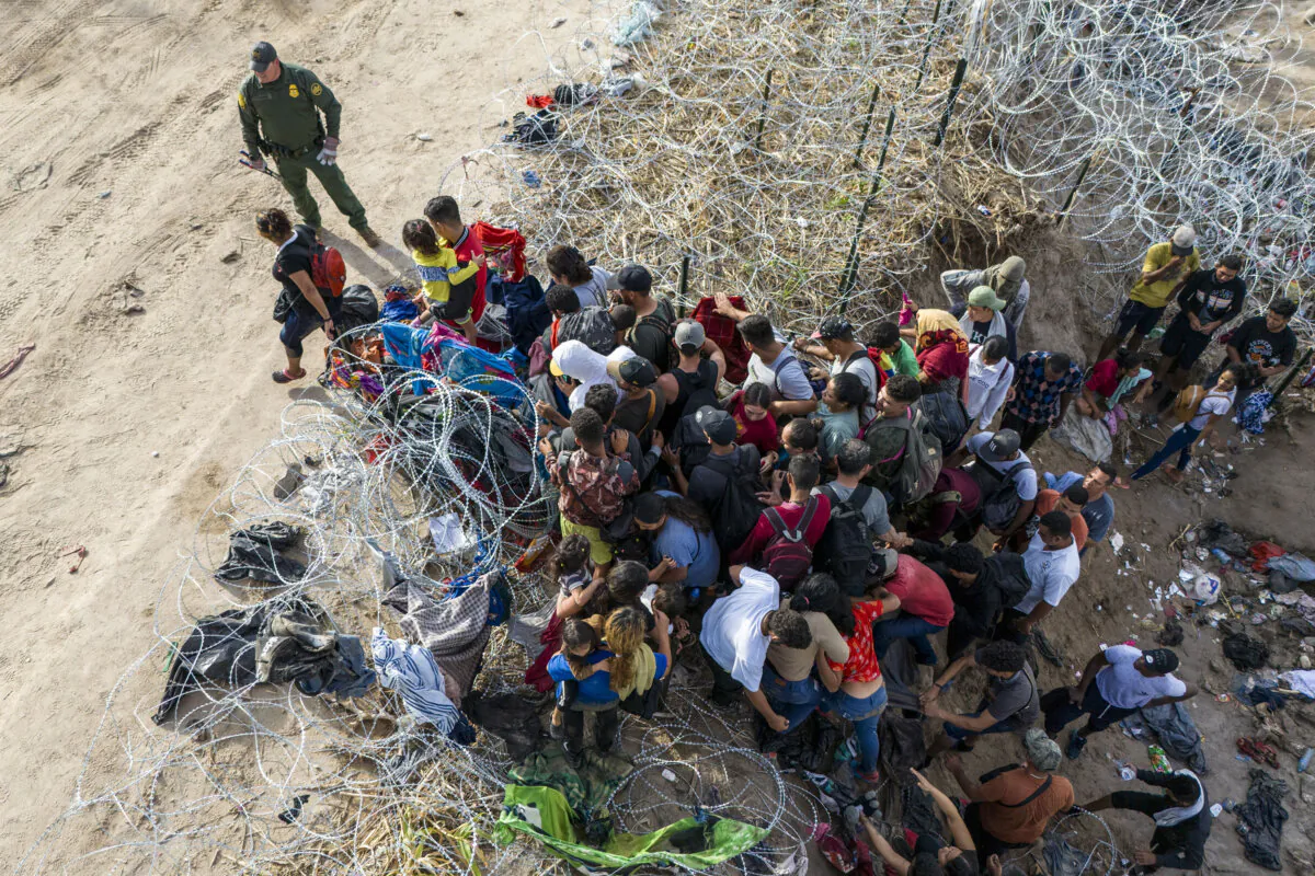 As seen from an aerial view a U.S. Border Patrol agent watches as illegal immigrants walk into the United States after crossing the Rio Grande from Mexico, in Eagle Pass, Texas, on Sept. 30, 2023. (John Moore/Getty Images)