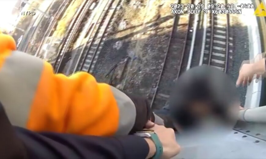 Teen rescued as train approaches while dangling above NYC tracks.