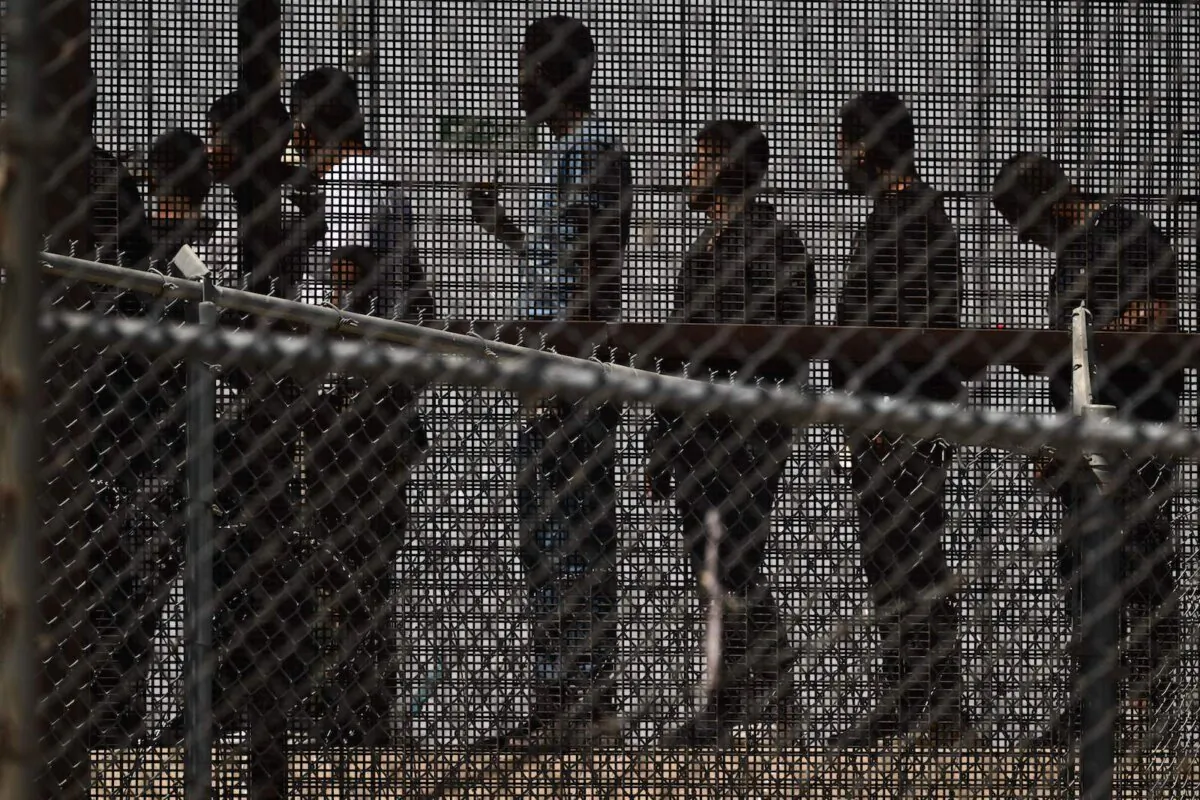 Illegal immigrants wait in along the border wall to board a bus after surrendering to U.S. Customs and Border Protection (CBP) Border Patrol agents on the U.S.-Mexico border in El Paso, Texas, on May 12, 2023. (Patrick T. Fallon/AFP via Getty Images)